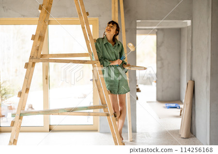 Woman painting while renovating a house Woman painting while renovating a house 114256168