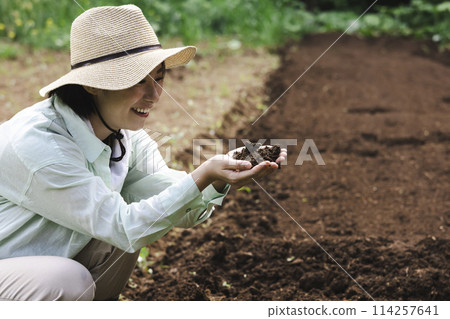 A woman checking the soil in a field 114257641