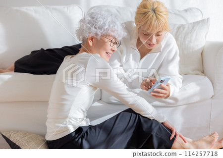 家庭：看著智慧型手機的母親和女兒 114257718