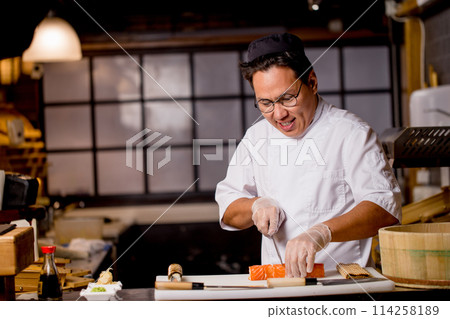 attractive Asian guy cutting a roll for clients attractive Asian guy cutting a roll for clients 114258189