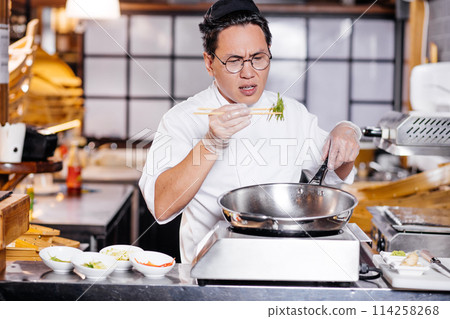 puzzled chef holding green with chopsticks 114258268