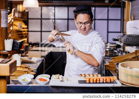 confident Asian chef is going to cut roll 114258279