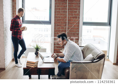 European gay male couple spend time together drinking coffee and watching laptop European gay male couple spend time together drinking coffee and watching laptop 114258361