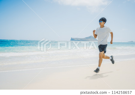 年輕人在夏威夷沙灘上沿著碧綠的海水奔跑 年輕人在夏威夷沙灘上沿著碧綠的海水奔跑 114258657