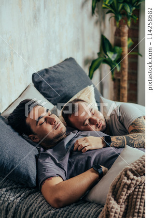Two handsome gay men, nude in bed together cuddling and smiling one of them has visible pecs and defined abs 114258682
