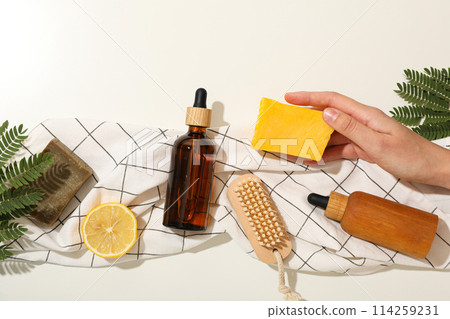 Bottles for serum, bars of soap in hand, lemon and brush on towel on  white background, top view 114259231