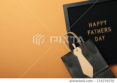 Inscription on a black board for Father's Day, on an orange background. 114259256