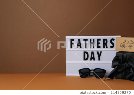 Inscription on a white chalkboard father's day, on a brown background, with gifts. 114259270