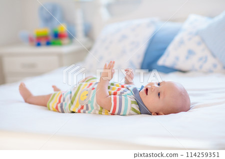 Little baby on white bed 114259351