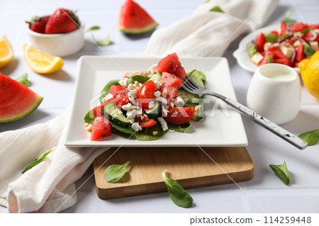Watermelon salad in a bowl with lemon and strawberries on a white background 114259448