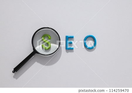 Letters SEO and magnifying glass on light background, top view 114259470