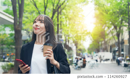 A female business person walking down the street with a smartphone 114260927
