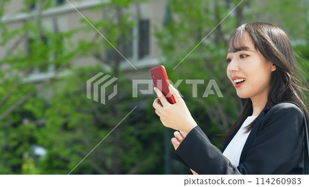 A female business person looking at her smartphone in the city A female business person looking at her smartphone in the city 114260983