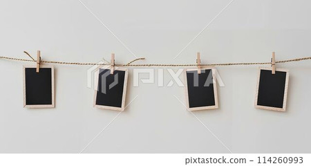 close up of a 4 blank note papers, photo frame on a rope with clothespins white background close up of a 4 blank note papers, photo frame on a rope with clothespins white background 114260993
