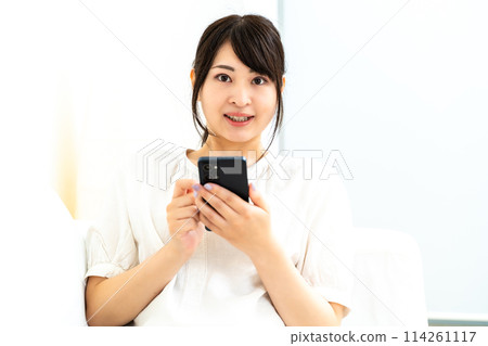 A woman using a smartphone at home 114261117