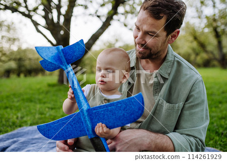 Father and toddler playing with foam glider plane. Single dad having fun with baby during warm spring day. Father's day concept. 114261929