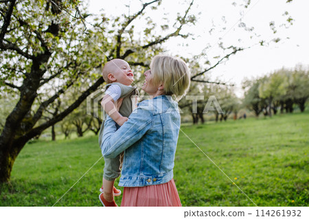Portrait of beautiful mature first time mother with small toddler, outdoors in spring nature. Portrait of beautiful mature first time mother with small toddler, outdoors in spring nature. 114261932