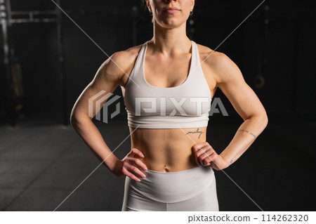 Front view of young muscular woman in gym. Routine workout for physical and mental health. Front view of young muscular woman in gym. Routine workout for physical and mental health. 114262320