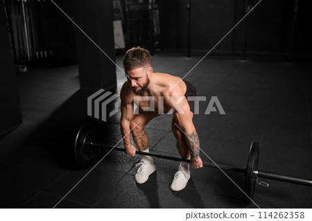 Strong man performing deadlift, lifting barbell from ground. Strength exercise. Routine workout for physical and mental health. 114262358
