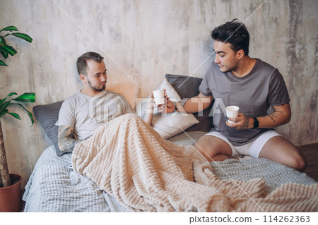 Perfect morning begins with lover and coffee in bed. Two guys resting in bed. Perfect morning begins with lover and coffee in bed. Two guys resting in bed. 114262363