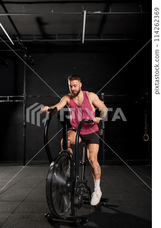Man exercising on elliptical cross-trainer machine, wearing activewear. Routine workout for physical and mental health. Man exercising on elliptical cross-trainer machine, wearing activewear. Routine workout for physical and mental health. 114262369
