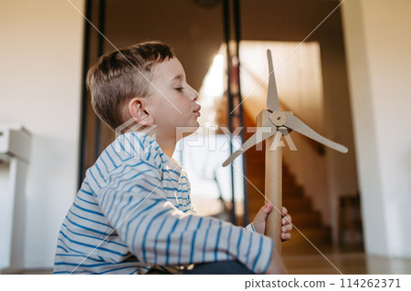 Boy holding wind turbine model. Concpet of renewable energy sustainable lifestyle for next generations. 114262371