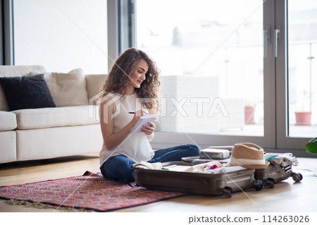 Beautiful woman planning summer vacation abroad, packing suitcase. Solo traveller preparing for trip. 114263026