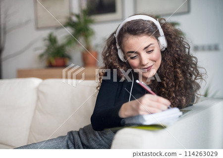 Beautiful woman listening travel podcast, planning summer vacation abroad, going on trip alone. Working on itinerary. Beautiful woman listening travel podcast, planning summer vacation abroad, going on trip alone. Working on itinerary. 114263029
