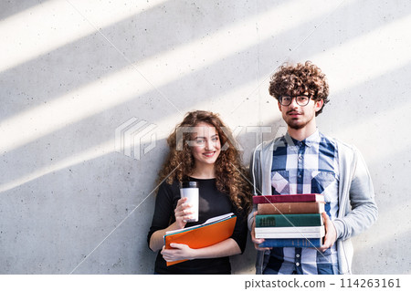 Young university students, holding stack of books, coffee, preparing for final exam. Study group. 114263161
