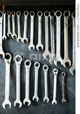 Combination wrenches set in auto repair shop. Mechanics repairing, maintaining car in garage. 114263421