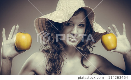 Woman in dress and hat hold yellow apple Woman in dress and hat hold yellow apple 114263464