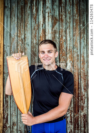 Portrat of young canoeist holding paddle. Concept of canoeing as dynamic and adventurous sport. 114263478