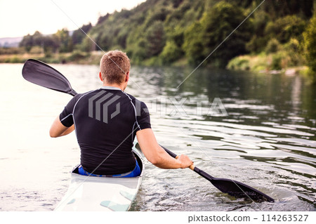 Canoeist man sitting in canoe holding paddle, in water. Concept of canoeing as dynamic and adventurous sport. Rear view, sportman looking at water surface, paddling Canoeist man sitting in canoe holding paddle, in water. Concept of canoeing as dynamic and adventurous sport. Rear view, sportman looking at water surface, paddling 114263527