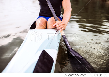 Close up of canoeist sitting in canoe holding paddle, in water. Concept of canoeing as dynamic and adventurous sport. Close up of canoeist sitting in canoe holding paddle, in water. Concept of canoeing as dynamic and adventurous sport. 114263533
