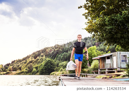Young canoeist carry canoe and paddle, going on water. Concept of canoeing as dynamic and adventurous sport. 114263534