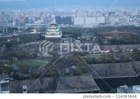 從天空鳥瞰大阪城，櫻花季節，生駒山脈，黃昏和夜景照亮的大阪城 114263684