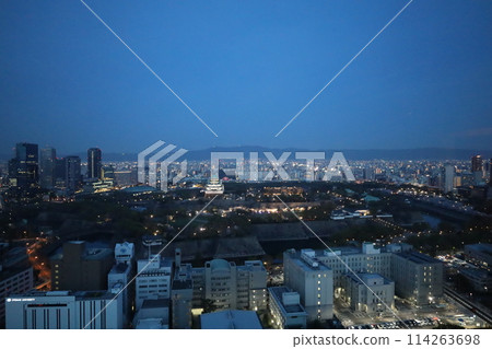 Bird's-eye view of Osaka Castle from the sky Cherry blossom season Ikoma mountain range Osaka Castle lit up at dusk and night 114263698