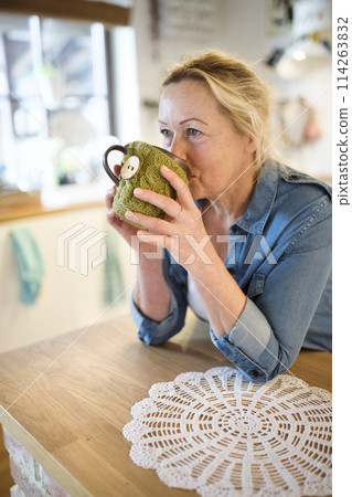 Beautiful mature woman at home, drinking hot tea at morning. Older woman living alone, enjoying peaceful weekend day 114263832
