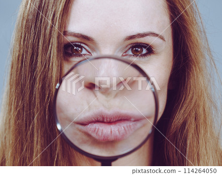 Woman showing lips in magnifer 114264050