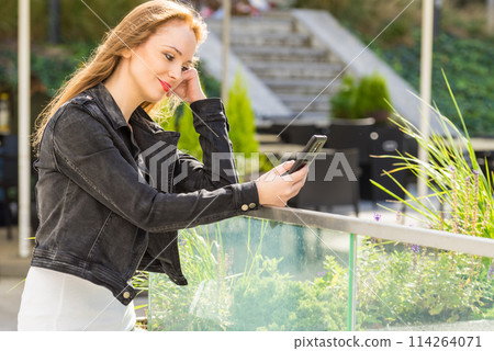 Girl using mobile phone on city street 114264071