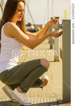 Woman drinking water from tap in marina. Woman drinking water from tap in marina. 114264123