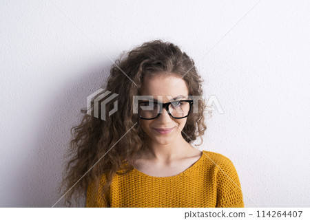 Portrait of a gorgeous teenage girl with curly hair and eyeglasses. Studio shot, white background with copy space Portrait of a gorgeous teenage girl with curly hair and eyeglasses. Studio shot, white background with copy space 114264407