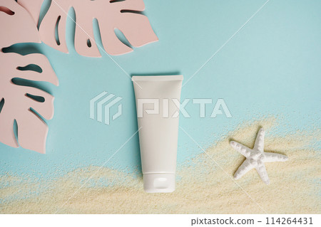 Cosmetic cream white tube mockup on blue background with sand, starfish and pink monstera leaves. Sunscreen with UVA and UVB protection 114264431