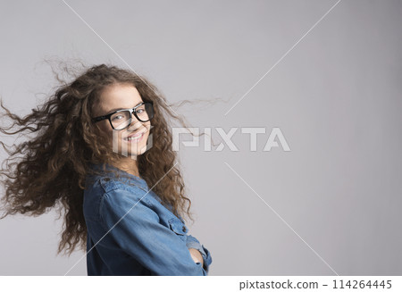 Portrait of a gorgeous teenage girl with curly hair and eyeglasses. Studio shot, white background with copy space Portrait of a gorgeous teenage girl with curly hair and eyeglasses. Studio shot, white background with copy space 114264445
