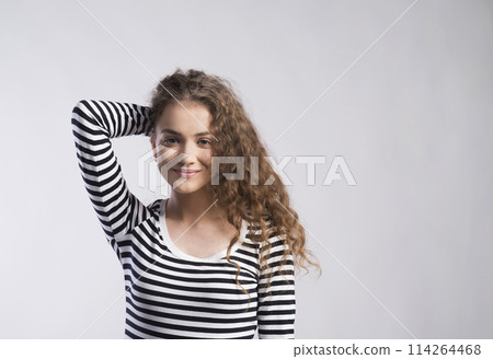 Portrait of a gorgeous teenage girl with curly hair. Studio shot, white background with copy space 114264468