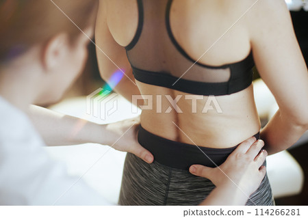 Medical massage therapist checking clients back condition 114266281