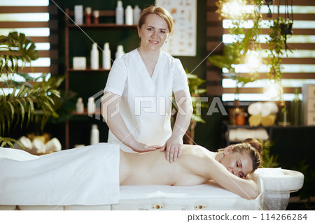 happy massage therapist in spa salon massaging clients back 114266284