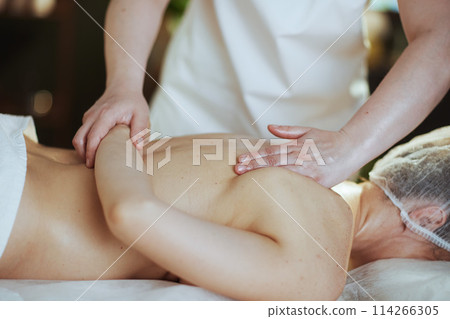 Medical massage therapist in massage cabinet massaging client 114266305