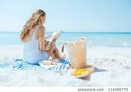 relaxed elegant woman on beach with straw bag 114266779