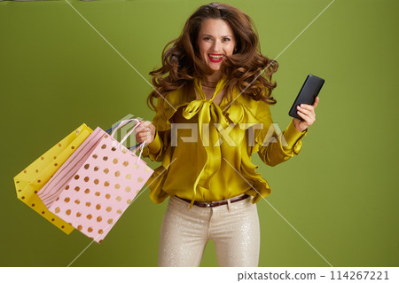 smiling modern woman using smartphone on green background 114267221